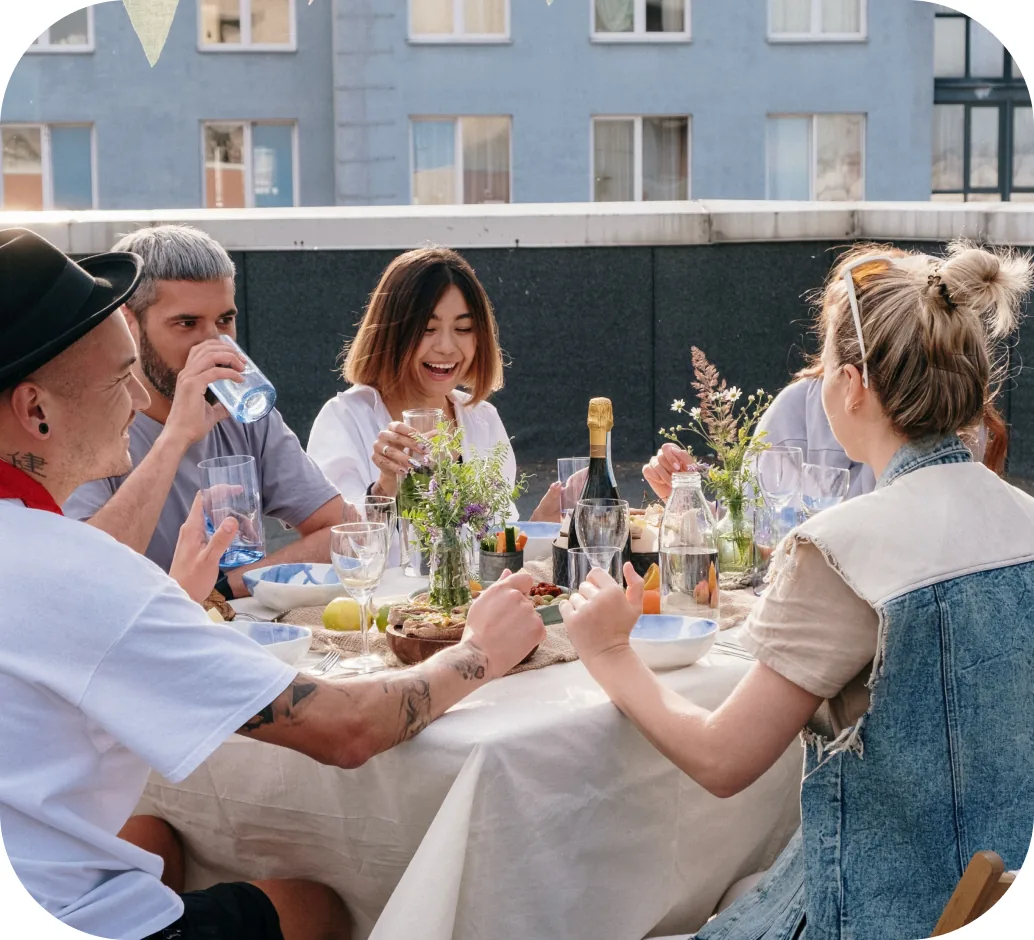 Friends laughing around a rooftop dinner table